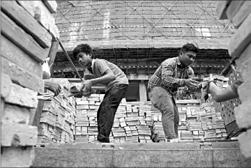  ??  ?? Unloading bricks at an under-constructi­on luxury high-rise building complex in Phnom Penh.