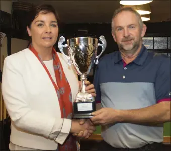  ??  ?? Deirdre Kehoe (niece) presents the Jim O’Neill memorial perpetual cup to winner Martin Kehoe after the competitio­n in his memory organised by the Three Bullet Gate Golf Society in New Ross.