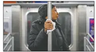  ?? (File Photo/AP/John Minchillo) ?? A subway passenger uses a tissue March 19, 2020, to protect her hand while holding onto a pole as covid-19 concerns drive down ridership in New York.