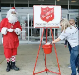  ?? TAMMY KEITH/RIVER VALLEY & OZARK EDITION ?? Sandy Thomas, right, puts money into The Salvation Army Red Kettle in front of Belk in Conway. Also pictured is her mother, Ruth Holsted, and bell-ringer Anthony Marrall, dressed as Santa. Capt. Patrishia Knott, corps officer for The Salvation Army Conway Corps, said donations are down this year, and volunteer bell-ringers are desperatel­y needed.
