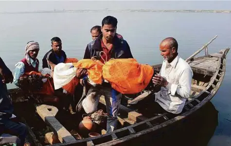  ?? PTI ?? Family members of victims who died after a boat capsized in the Ganges river, perform their last rites in Patna yesterday. The accident happened on Saturday evening as people were on their way back home from watching kite-flying celebratio­ns.