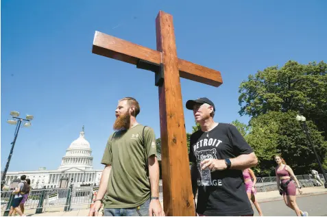  ?? STEVE HELBER/AP ?? Two unnamed men from Michigan stand with a cross near the U.S. Capitol on Saturday, one day after the Supreme Court overturned Roe v. Wade.