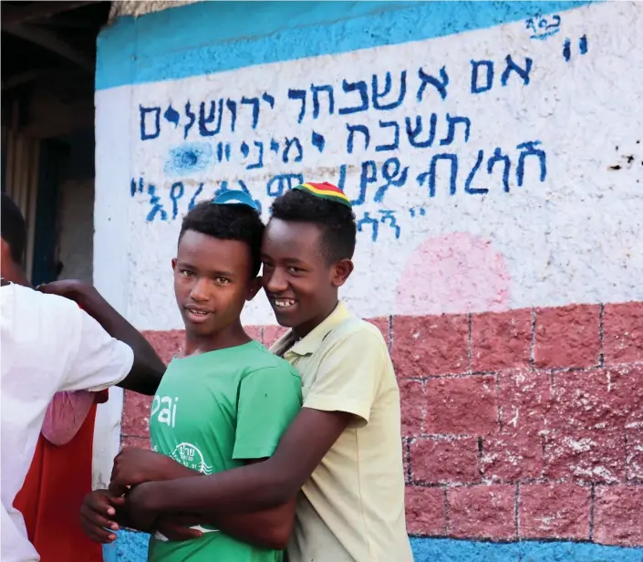  ??  ?? TWO BOYS before morning services at the Hatikva Synagogue in Gondar. In the back, the famous text reads: ‘If I forget you, O Jerusalem, may my right hand forget [its skill].’ (Psalms 137 verse 5)