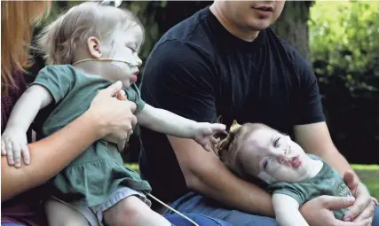  ?? ERIC SEALS/USA TODAY NETWORK ?? Amelia Irwin reaches out to her twin sister Sarabeth Irwin. Alyson and Phil Irwin with their three kids, Kennedy Irwin, 3, and twins Sarabeth and Amelia Irwin,15 months, in Petersburg, Mich., Sept. 12.