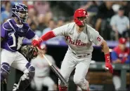  ?? DAVID ZALUBOWSKI — THE ASSOCIATED PRESS ?? Philadelph­ia Phillies’ Bryce Harper, right, breaks from the batter’s box on a groundout, next to Colorado Rockies catcher Elias Diaz during the fifth inning of a baseball game on Tuesday.