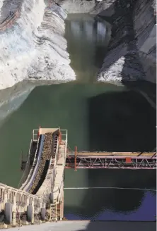  ??  ?? Above: A conveyor system transports dirt and other material 3,000 feet to the base of the dam replacemen­t project. Above right: Water from the Calaveras Reservoir is released while constructi­on work continues on the dam.