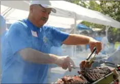  ??  ?? Peter Psomiadis barbecues
racks of ribs during
the food festival at St. Philip’s Antiochian Orthodox
Church.