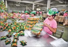  ?? HONG MENEA ?? Workers bundle packaged goods into plastic bags at the LYLY Food Industry Co Ltd factory in Phnom Penh’s Por Sen Chey district in 2015.