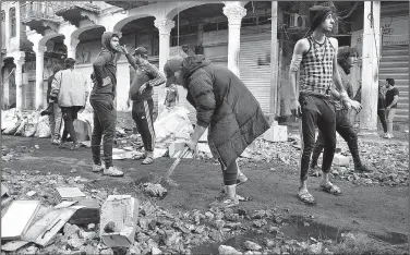  ?? AP/HADI MIZBAN ?? Anti-government protesters in Baghdad clean Rasheed Street, which was damaged Sunday in clashes between the demonstrat­ors and security forces.