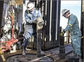 ?? Bloomberg News/MATTHEW BUSCH ?? Precision Drilling oil rig operators install a bit guide on the floor of a Royal Dutch Shell oil rig near Mentone, Texas, in early March.