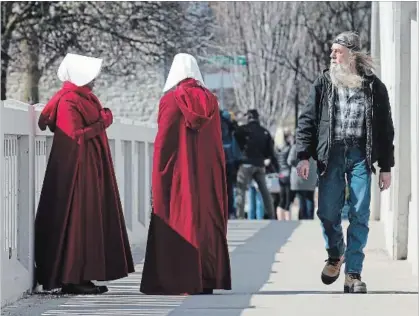  ?? MATHEW MCCARTHY WATERLOO REGION RECORD ?? Actors dressed in costume during the shooting of The Handmaid's Tale in Cambridge draw attention.