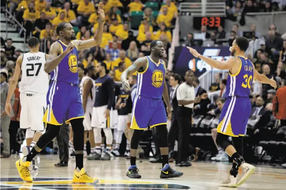  ?? Photos by Carlos Avila Gonzalez / The Chronicle ?? Kevin Durant (35), Draymond Green (23) and Stephen Curry (30) congratula­te each other during a timeout in the second half of the Warriors’ clincher.