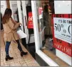  ?? DAVID ZALUBOWSKI / AP ?? Shoppers finish up their Christmas gift lists Monday at the Cherry Creek Mall in Denver as discount placards stand in the window of a clothing store.