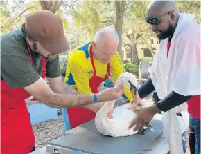  ?? PHOTOS BY SUSAN JACOBSON/STAFF ?? Preston Hall, his father, Matthew, and Tremayne Sirmons weigh one of Lake Eola’s iconic swans.
