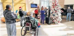  ?? JOE BURBANK/ORLANDO SENTINEL ?? Veterans listen to members of the Orlando Opera chorus perform Christmas carols Thursday in the lobby of the Orlando VA Medical Center at Lake Nona.