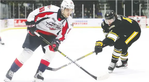  ?? MARK MALONE ?? The Spitfires’ Chris Playfair gets past the Sting’s Sam Bitten in the second period at Progressiv­e Auto Sales Arena in Sarnia Friday night. Windsor won 5-4 in a shootout.