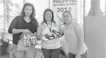  ??  ?? Filipina Olympic lifter Hidilyn Diaz (R) and Jude Sulla (L) of CWA donate two pairs of shoes to Tagbilaran weightlift­ing team coach Jona Alegada (C) during the press launch of CWA's free weighlifti­ng seminar yesterday at Osting's Restaurant in the City...