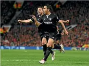  ?? PHOTOS: AP/GETTY IMAGES ?? Manchester United striker Romelu Lukaku, left, cuts a dejected figure afte missing a chance while Sevilla players, right, celebrate their opening goal in the Spanish team’s 2-1 Champions League triumph.