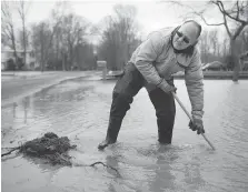  ?? DAX MELMER ?? Randy Stroud tries to clear the drain in front of his Cotterie Park Road home on Monday north of Hillman Marsh.