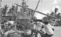  ??  ?? Workers pull a fallen electric pylon damaged by Typhoon Phanfone in Philippine­s. — AFP