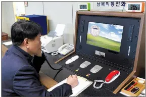  ?? AP ?? A South Korean government official talks with a North Korean officer Wednesday during a call on the dedicated hotline at the South Korean village of Panmunjom. North Korean leader Kim Jong Un reopened the communicat­ion channel on Wednesday.