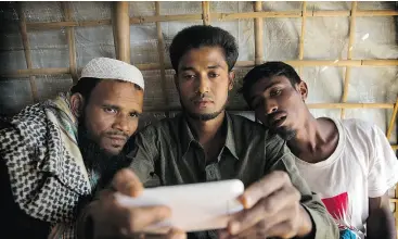  ??  ?? Rohingya Muslim refugee Mohammad Karim, centre, shows a mobile video of Gu Dar Pyin’s massacre to other refugees in Bangladesh’s Kutupalong refugee camp.