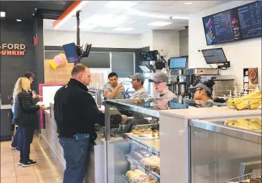  ?? Luther Turmelle / Hearst Connecticu­t Media ?? Dunkin’ Donuts employees at the 1101 North Colony Road location in Wallingfor­d wait on a customer Thursday. The location is one of two in Connecticu­t debuting the chain’s “store of the future” concept.