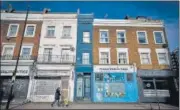  ?? AFP ?? A pedestrian passes by what is dubbed 'London's thinnest house' (painted blue) in London.