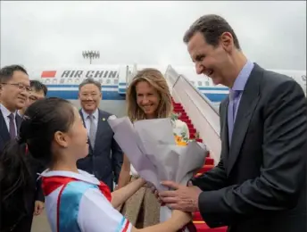  ?? SANA/AFP via Getty Images ?? Syria President Bashar al-Assad, right, and first lady Asma al-Assad are welcomed upon their arrival at the airport Thursday in Beijing. Mr. Assad began his first official trip to China in almost two decades as the Arab leader seeks financial support to help rebuild his devastated country.