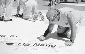  ?? CAITLIN FAW/BALTIMORE SUN ?? Douglas Hott of Parkville, who served with the Navy in Da Nang from 1965 to 1967, signs his name on the Vietnam “Tour of Duty Map” during the LZ Maryland tribute at the state fairground­s.