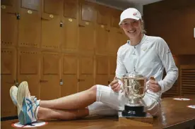  ?? Photograph: Corinne Dubreuil/AP ?? Iga Swiatek poses with the trophy in the locker room after winning the French Open.