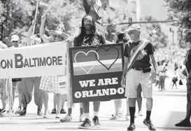  ??  ?? A member of AIDS Action Baltimore carries a sign that reads "We Are Orlando" in the parade, commemorat­ing the victims of June’s mass killing.