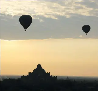  ?? ESTHER HTUSAN/THE ASSOCIATED PRESS ?? Hot air balloons carrying tourists are silhouette­d against the rising sun as they fly over the ancient Myanmar city of Bagan.