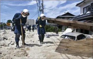  ?? SHINGO NISHIZUME — KYODO NEWS VIA AP ?? Police use sticks during a search operation Wednesday at a mud-covered area in the aftermath of heavy rains in Kure, Hiroshima prefecture, southweste­rn Japan. Rescuers combed through mud-covered hillsides and along riverbanks Tuesday searching for dozens of people missing after heavy rains unleashed flooding and mudslides in Japan.