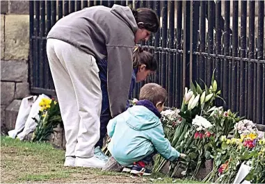  ?? ?? Respect: Three children add their contributi­ons to the growing array of floral tributes