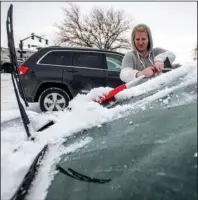  ?? The Associated Press ?? WINTRY WEATHER: Brittany Culp brushes snow off of her windshield on a windy and snowy Saturday morning in Greeley, Colo.. The weather caused the city to cancel its annual Greeley Lights the Night parade, which was scheduled in the evening.