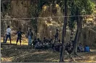  ?? (AP/Shafiqur Rahman) ?? Members of the Myanmar Border Guard Police, dressed in civilian clothing, sit under trees on Monday after abandoning their posts as Bangladesh border guards stand guard in Ghumdhum, Bandarban, Bangladesh.