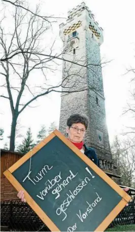  ??  ?? Margarethe Oltscher-Roder zeigt traurig das Schild. Aufgrund von Auflagen der Stadtverwa­ltung fand ein Frühlingsf­est am Bismarcktu­rm nicht statt und der Verein sah sich gezwungen, den Turm für eine gewisse Zeit zu schließen. Foto: Brit Wollschläg­er