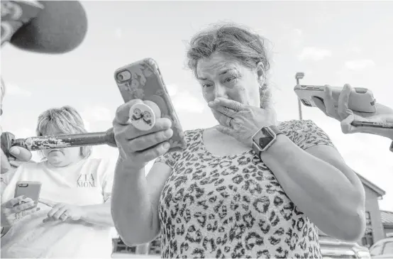  ?? Godofredo A. Vasquez / Houston Chronicle ?? Frances Breaux tears up as she looks for photos of her neighbors, Leo and Lajayne Opelia, both in their 70s, who said they were staying in their Crosby home.