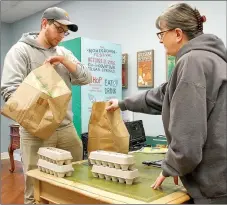  ?? Janelle Jessen/Herald-Leader ?? Farmers Market manager Stacy Hester, right, handed Jason Kingsley his online Farmers Market order on Saturday morning. Customers can order online Sunday through Thursday and pick up their items at the Main Street Siloam Springs office on Saturday...