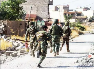  ?? ODD ANDERSEN/AFP ?? Peshmerga fighters run for cover across a section exposed to sniper fire as the Iraqi Kurdish forces pushed deeper into the town of Bashiqa, near Mosul, during battles against Islamic State on Tuesday.