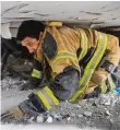  ??  ?? Ein Feuerwehrm­annsucht in einem zerstörten Gebäude nach Menschen.