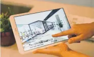  ??  ?? Sarah Stone of NAVA Real Estate Developmen­t uses a tablet to show images from the VR goggles for the tour of the yet-to-be-built condos.