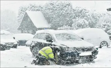  ?? BEN STANSALL / AGENCE FRANCE-PRESSE ?? A man fits snow chains to his car in the village of Brenchley in southeast England on Tuesday, as icy temperatur­es persist across the country.