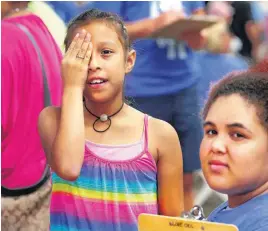  ??  ?? With her hand covering her right eye, Hatziry Garcia, 9, reads an eye chart while volunteer Arieyana Blackwell, of Edmond, checks her vision accuracy Saturday during LOVE OKC One Day at State Fair Park.