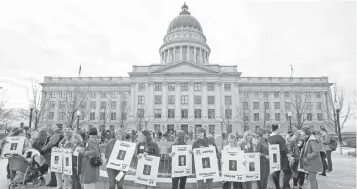  ?? RICK BOWMER, AP ?? Women in red hold signs with photos of their lawmakers Wednesday at the Utah Capitol in Salt Lake City to remind legislator­s they’re closely watching how they handle women’s issues.