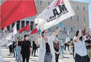  ?? PETROS GIANNAKOUR­IS THE ASSOCIATED PRESS ?? Protesters wave flags during a May Day rally outside the Greek parliament in Athens on Friday.