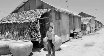  ??  ?? Chhum Long, whose daughter was a surrogate mother, stands in front of her house in the village of Puth Sar in Takeo province. — AFP photo