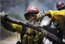  ?? ERIC PAUL ZAMORA/THE FRESNO BEE VIA AP ?? A Kings River Hotshot cuts down and remove limbs from trees along Sandy Road near where the Railroad Fire continues to burn Wednesday near Fish Camp.