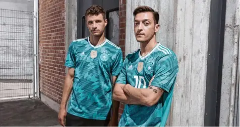  ?? Foto: adidas/dpa ?? Das gewohnte Spiel: Vor jedem Turnier schlüpft die deutsche Nationalma­nnschaft in neue Trikots. Hier präsentier­en Thomas Müller und Mesut Özil (rechts) das neue Aus wärtsshirt der DFB Elf.